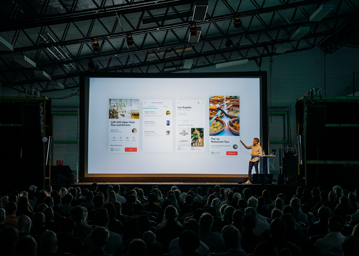 man presenting his materials in front of a audience using posters